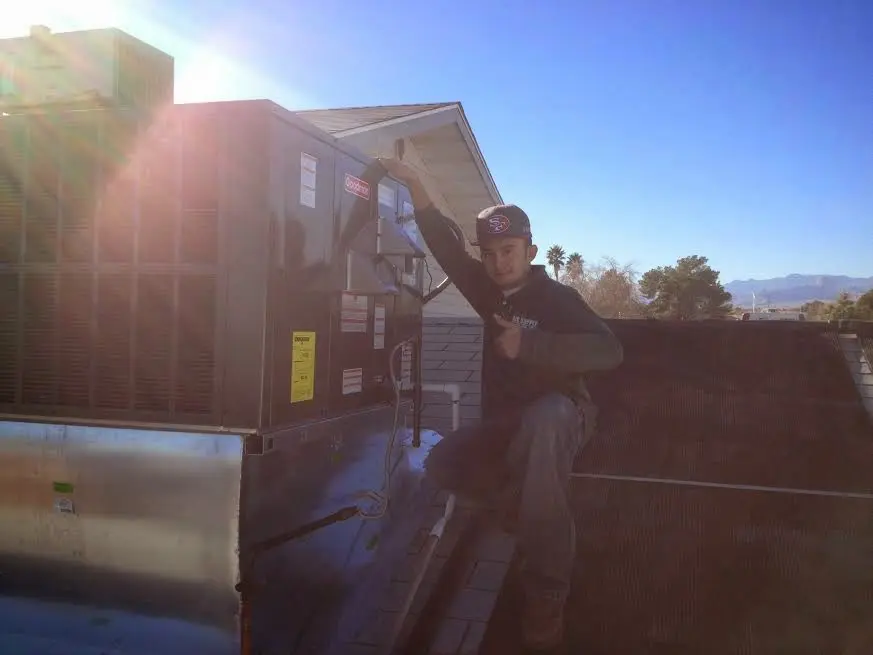 HVAC technician performing Air Duct Cleaning on a rooftop unit in Marcy
